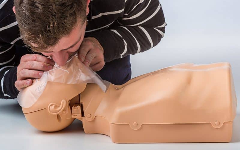 Mouth CPR. A man performing cpr on a manikin